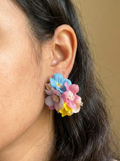 Close-up of an ear wearing colorful floral earrings with a blurred background