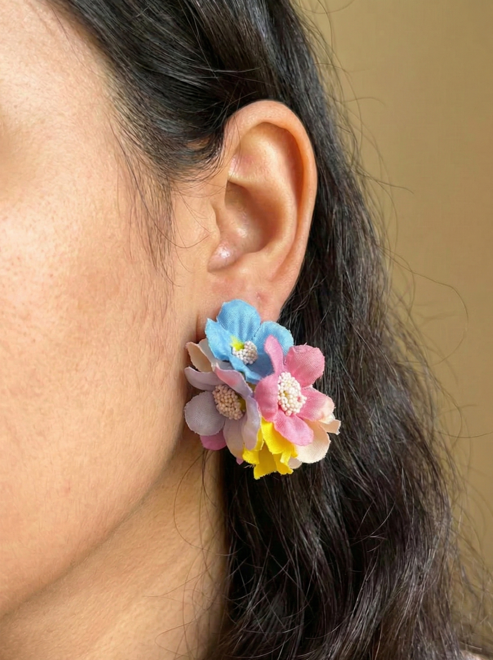 Close-up of an ear wearing colorful floral earrings with a blurred background