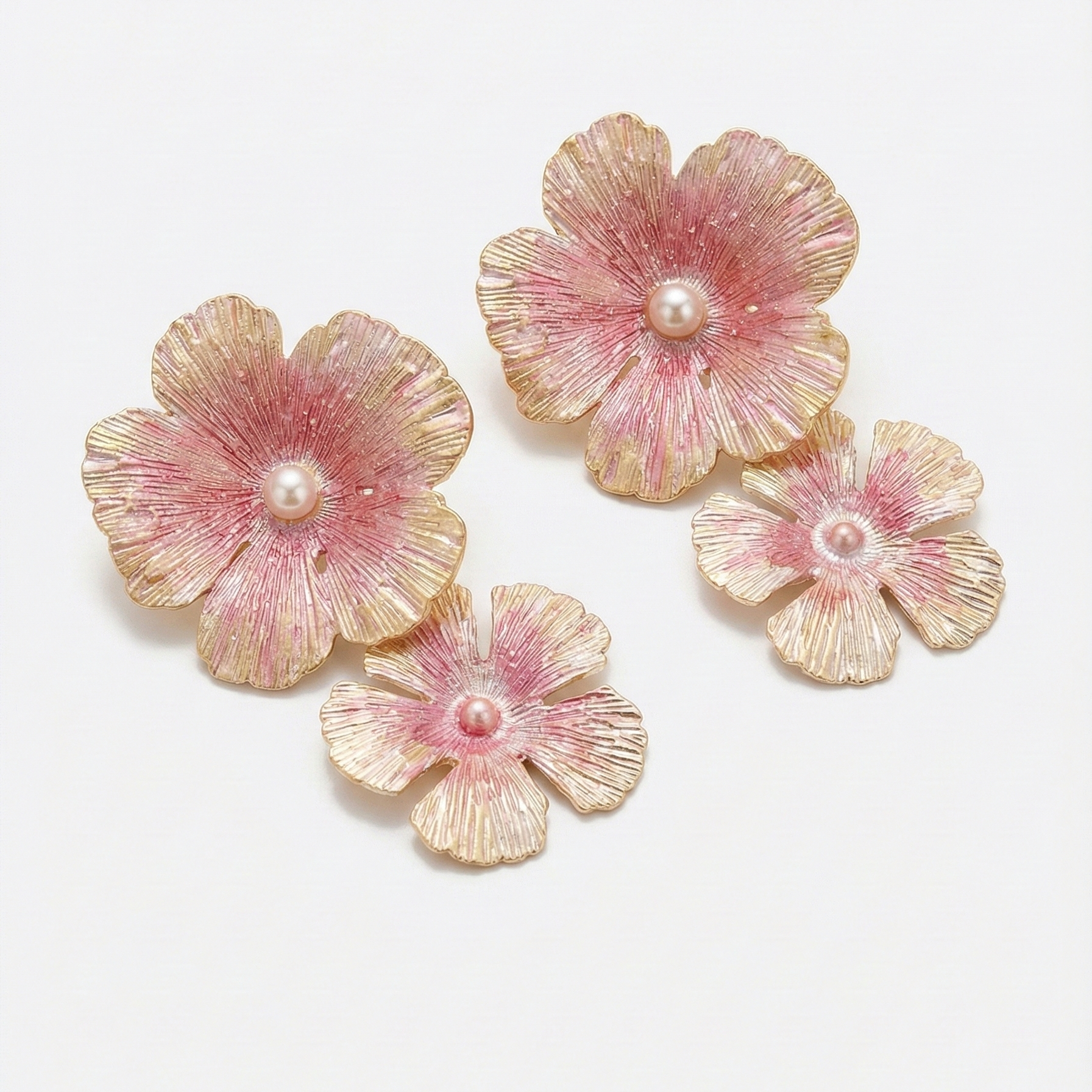 Set of pink and gold flower-shaped earrings on a white background