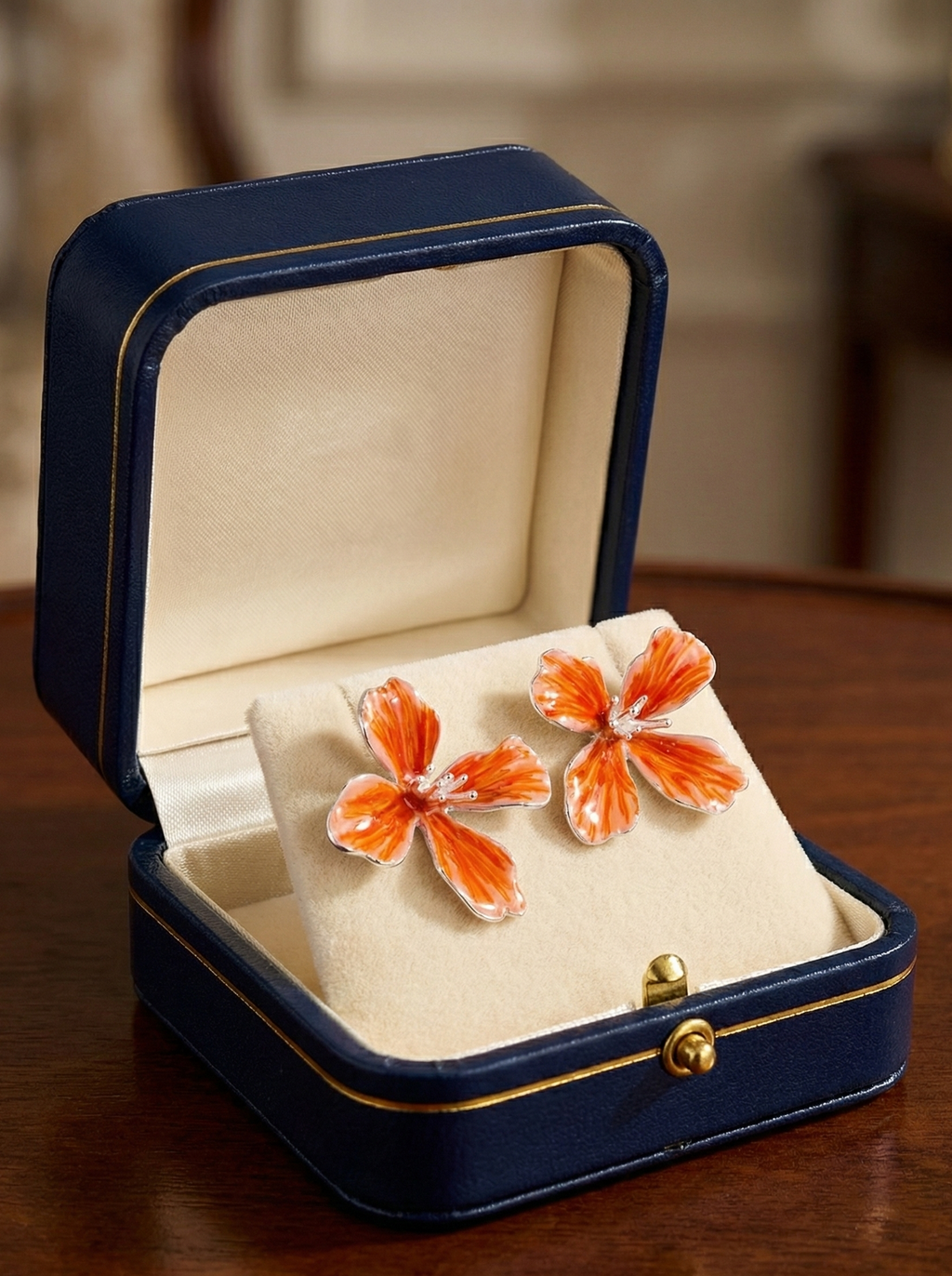 Butterfly-shaped earrings in a blue jewelry box on a wooden surface