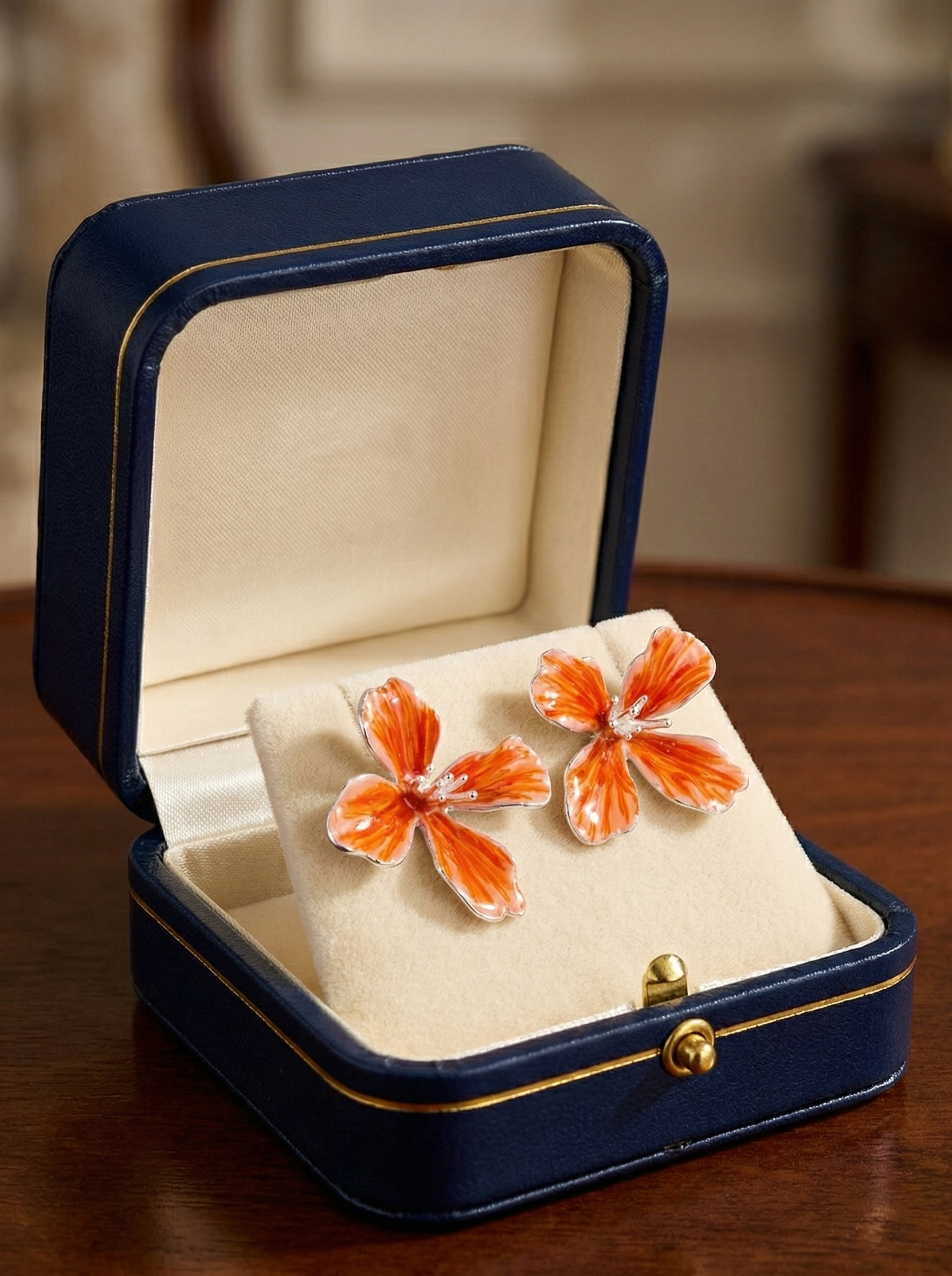 Butterfly-shaped earrings in a blue jewelry box on a wooden surface